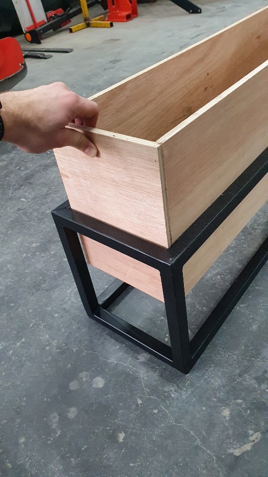 The wooden trough seated inside the welded black metal frame during assembly
