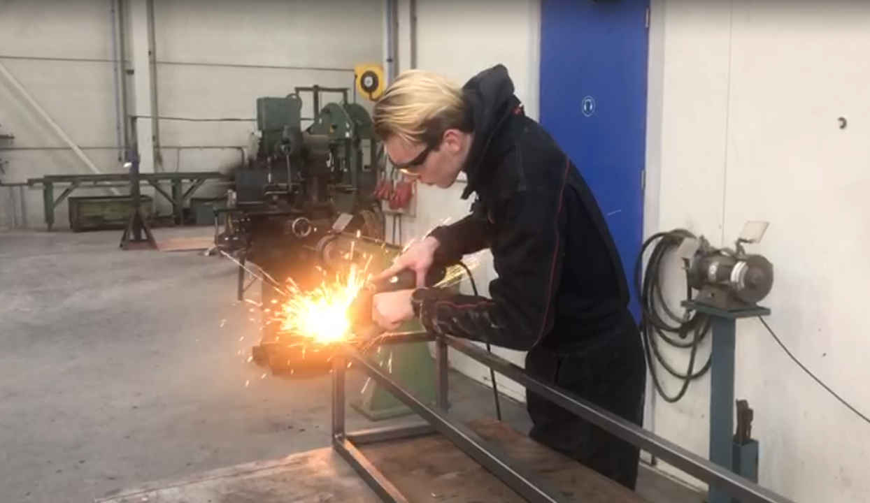 Roan grinding the steel frame in the workshop, sparks flying